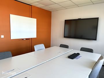 Salle de réunion lumineuse de 6 personnes avec tableau blanc et écran de projection